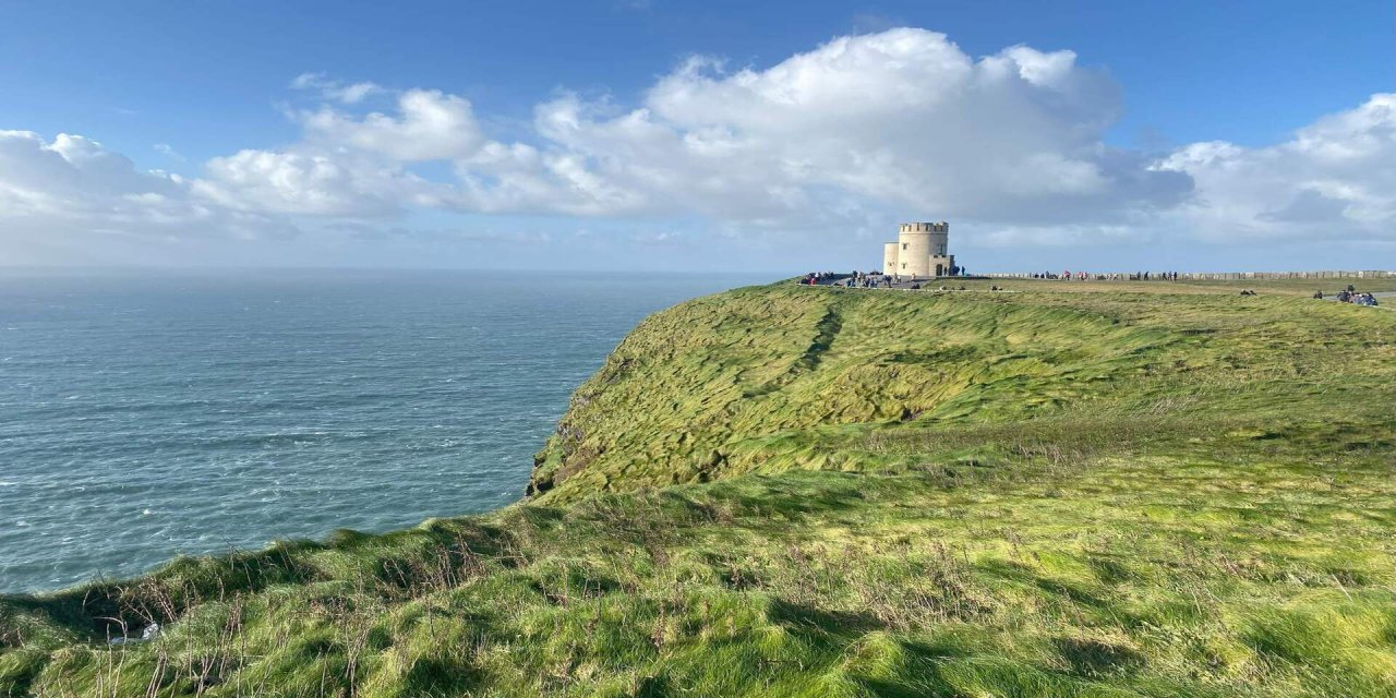 people in the distance exploring the cliffs of moher