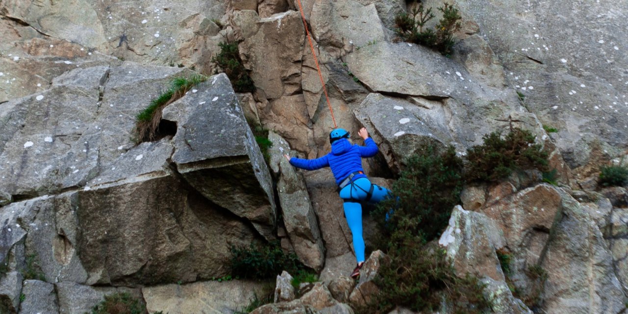 Woman rock climbing while attached to a harness 