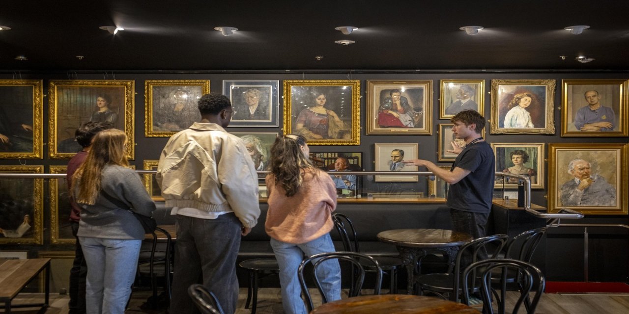 Guests looking at pictures in gold frames on wall