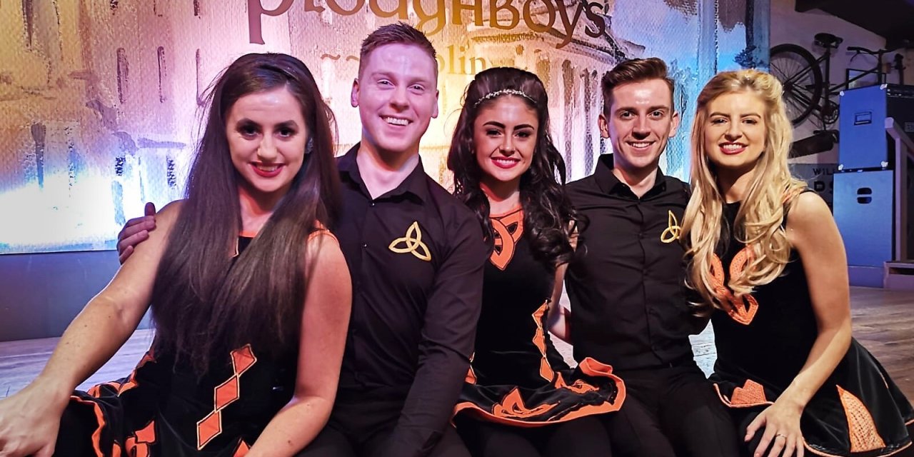 Five dancers from the Merry Ploughboy Dance Show posing and smiling