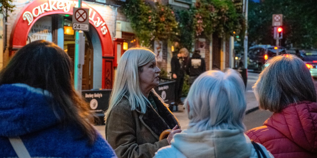 Woman with white blonde hair talking to crowd during haunted tour